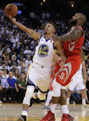 No joy: Golden State Warriors' Stephen Curry (left) lays up a shot past Houston Rockets' PJ Tucker in the opening game of the new NBA season.
