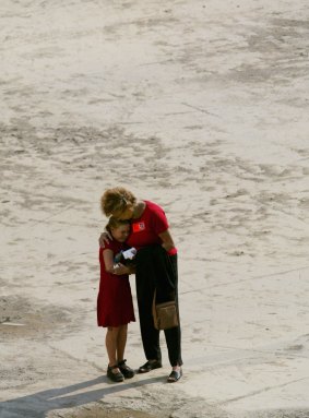 A young mourner is consoled as she visits the pit of ground zero in New York on the first anniversary of 9/11.