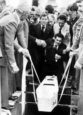 Essendon 1978: Sam Gulle is supported by friends as the body of his 4-week-old son is lowered into the grave.
