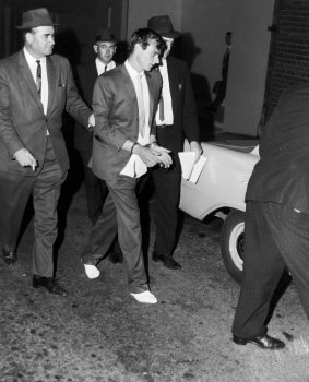 Peter Walker is led in to police headquarters in Sydney after his recapture in January 1966.
