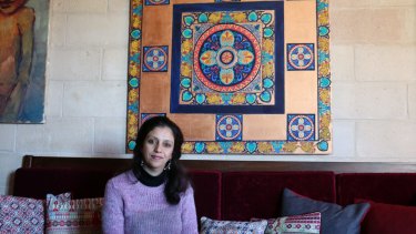 Palestinian artist Maha al-Daya, 39, sits in front of one of her works in her apartment in Gaza. 
