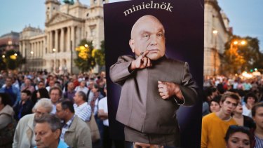 A man holds a banner depicting Hungarian Prime Minister Viktor Orban which reads "mini-prime minister" during a protest against Orban's policies in Budapest.