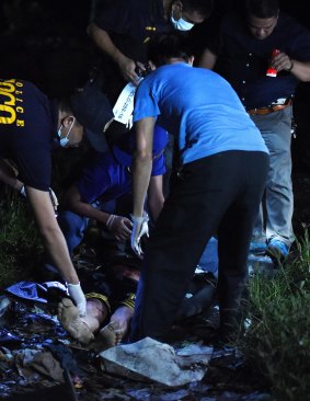 Police inspect the scene of one of the three men slain in a drug related killing in Caloocan, Manila, Philippines. 