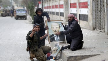 Rebel fighters deface pictures of Hafez al-Assad in Idlib.