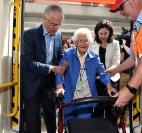 Mr Turnbull helps Frances Pearse, who will turn 100 tomorrow, onto a train carriage.