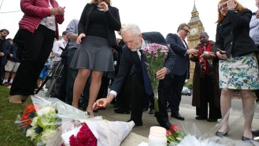 Labour Party leader Jeremy Corbyn, centre, lays a candle at an impromptu vigil at Parliament Square.