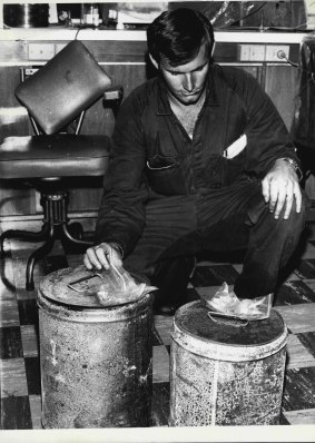 A detective examines two petrol drums found in the foyer of Brisbane Whiskey Au Go Go in 1973.