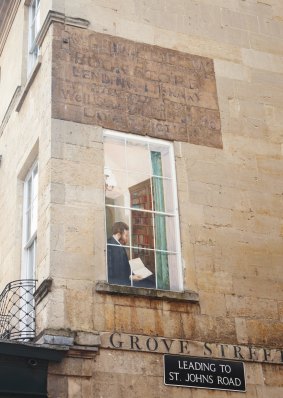 A mural depicts a man in a window, reading in the city of Bath, a UNESCO historic world heritage site.
