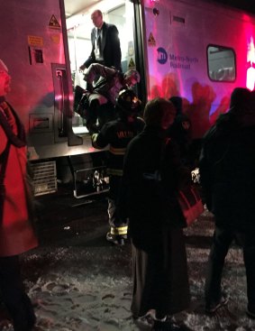 Passengers are assisted off the passenger train north after the collision north of New York City.