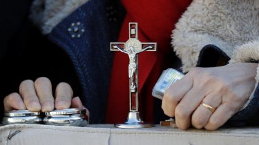 A woman holds her holy items as she attends Pope Francis' weekly general audience, in St. Peter's Square, at the Vatican.