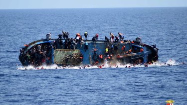 People jump out of a boat right before it overturns off the Libyan coast in 2016.