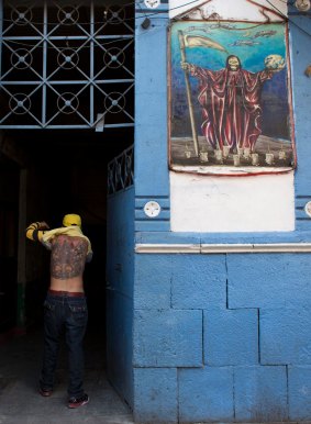 A man lifts his shirt to flash a tattoo of La Santa Muerte, or Saint Death.