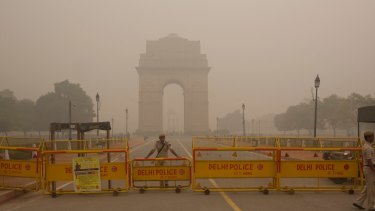 A Delhi policeman stands guard at the closed war memorial, which is engulfed in a thick smog.