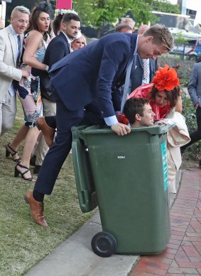 A racegoer is pushed into a rubbish bin at Flemington on Tuesday evening.