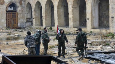 Syrian troops and pro-government gunmen marching walk inside the destroyed Grand Umayyad mosque in the old city of Aleppo, Syria.