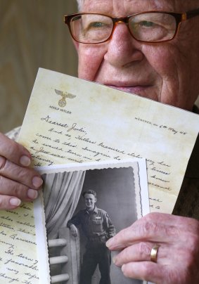 Danny Jacobson holds a photo copy of a letter written on Adolf Hitler's stationary with a photo of himself in uniform in World War II.