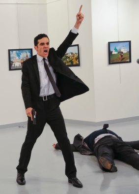 Turkish police officer Mevlut Mert Altintas gestures while shouting as the body of Russian Ambassador to Turkey, Andrei Karlov, lies at his side.