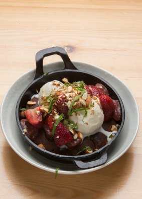 The skillet-cooked chocolate brownie is topped with roasted strawberries.
