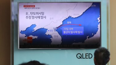 People sit in front of the TV screen showing a news program reporting about North Korea's missile firing, at Seoul Train Station in Seoul, South Korea.