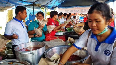 People prepare meals for evacuees at the Swecapura sports centre in Klungkung, Bali.
