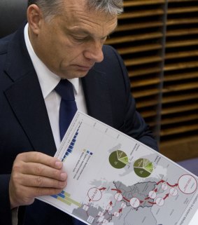 Hungarian Prime Minister Viktor Orban holds a document outlining migration routes prior to a round table meeting at an EU summit in Brussels on October 25.