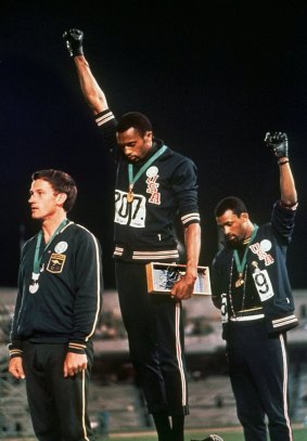 Australian Peter Norman (left) showed support for US athletes Tommie Smith, centre, and John Carlos as they stared downward during the playing of <i>The Star-Spangled Banner</I> at the 1968 Olympics.