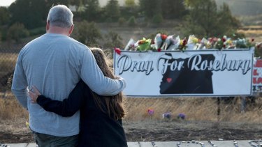 Dave and Robin Griffiths leave flowers at a memorial along the road to Umpqua Community College where nine people were gunned down.
