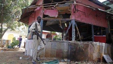 A Somali soldier walks past the restaurant following a suicide bombing.