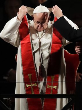 Pope Francis removes his stole after presiding over the Via Crucis  procession in front of Rome's Colosseum. 