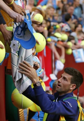 Playing up to the crowd: Djokovic signs post-match autographs.