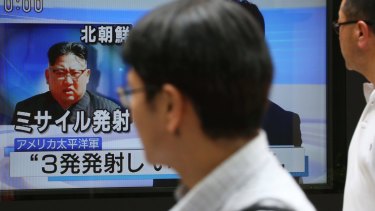 Passers-by watch a TV news program showing image of North Korean leader Kim Jong-un, in Tokyo.
