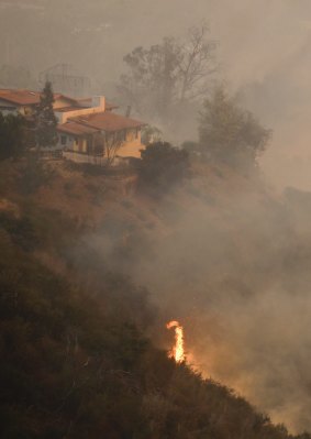 Flames burn toward a home during a wildfire Saturday, Dec. 16, 2017, in Montecito, Calif. (AP Photo/Chris Carlson)