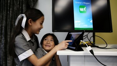 Emma Yap showing her younger sister Hannah the app she created, Emma's Wagon. 