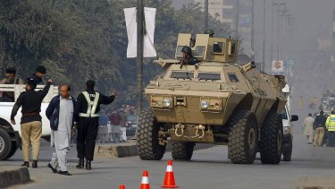 An armoured personnel carrier moves toward a school under attack by Taliban gunmen in Peshawar.