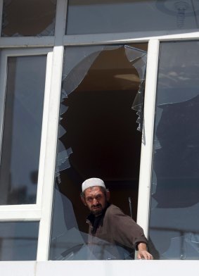 A man removes broken glass from a window after Monday's suicide attack in Kabul.