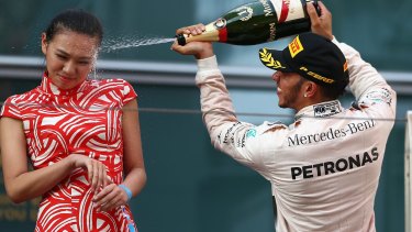 Under fire: Lewis Hamilton sprays champagne in the face of a Formula One hostess.