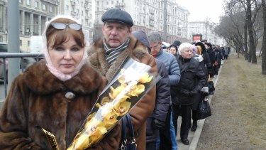 A Russian woman holds orchids at the front of a line for the funeral of Boris Nemtsov.