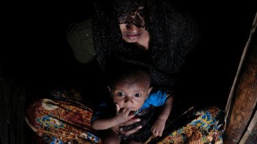 Mohsena Begum, a Rohingya who escaped to Bangladesh from Myanmar, sits with her child in an unregistered refugee camp in Bangladesh.