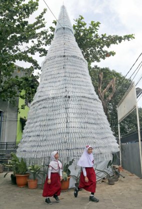 Two school girls walk past a Christmas tree made from 6000 discarded water bottles outside of a church in Depok, Indonesia, this week. 