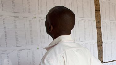 A Kenyan goes through the names posted on the wall of people who will vote at a polling station.