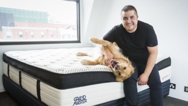 OzMattress owner Stefan Papas with his dog Mac on one of the mattresses manufactured by his company.