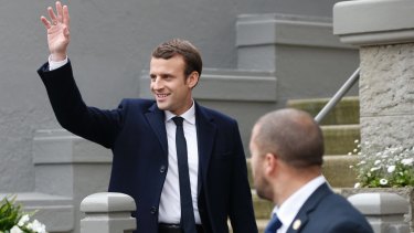 Emmanuel Macron waves to supporters as he leaves his house.