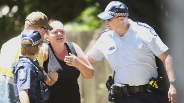 Police try to comfort a woman in Murray Street, Manoora, outside the Cairns house where the bodies of eight children were found.