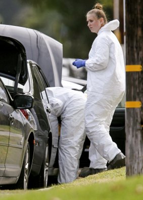 FBI agents investigate a car near a home in connection to the shootings in San Bernardino, California.
