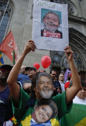 A demonstrator wearing a mask with the likeness of former president Lula and holding a picture of him with the word "friend" in Sao Paulo on Thursday.