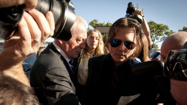 Amber Heard and her husband, actor Johnny Depp, work their way through a media scrum outside Southport Magistrates Court.