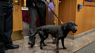 A police officer walks a bomb detection dog out of the Federal Communications Commission (FCC) meeting room during an evacuation at an open commission meeting in Washington, DC.