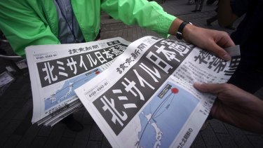 A man, left, distributes an extra edition of a newspaper reporting about North Korea's missile launch, at Shimbashi Station in Tokyo.