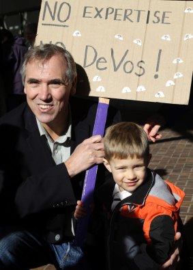Senator Jeff Merkley, a Democrat, poses with boy and his sign for a family member during a rally in Portland, Oregon.