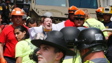Rescue personnel help injured people after a car ran into a large group of protesters.